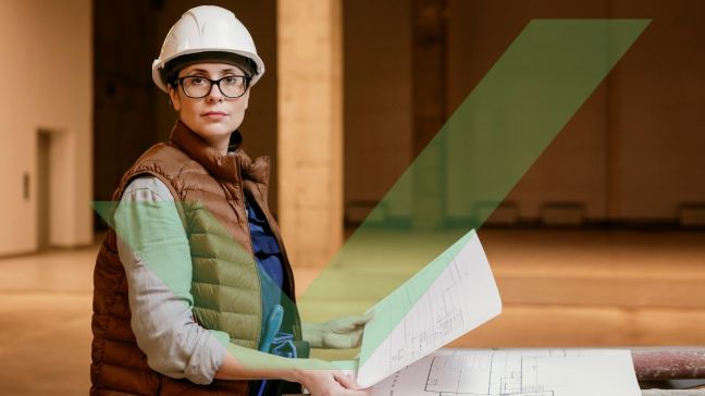 A female access consultant wearing a hardhat is staring at the camera while holding an architectural drawing with VAC Green tick