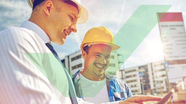 A male access consultant is holding a tablet PC and pointing at something on the screen to show a male project manager with VAC Green tick