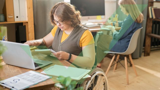 Young manager with a disability using a wheelchair in casualwear in front of laptop with VAC Green tick